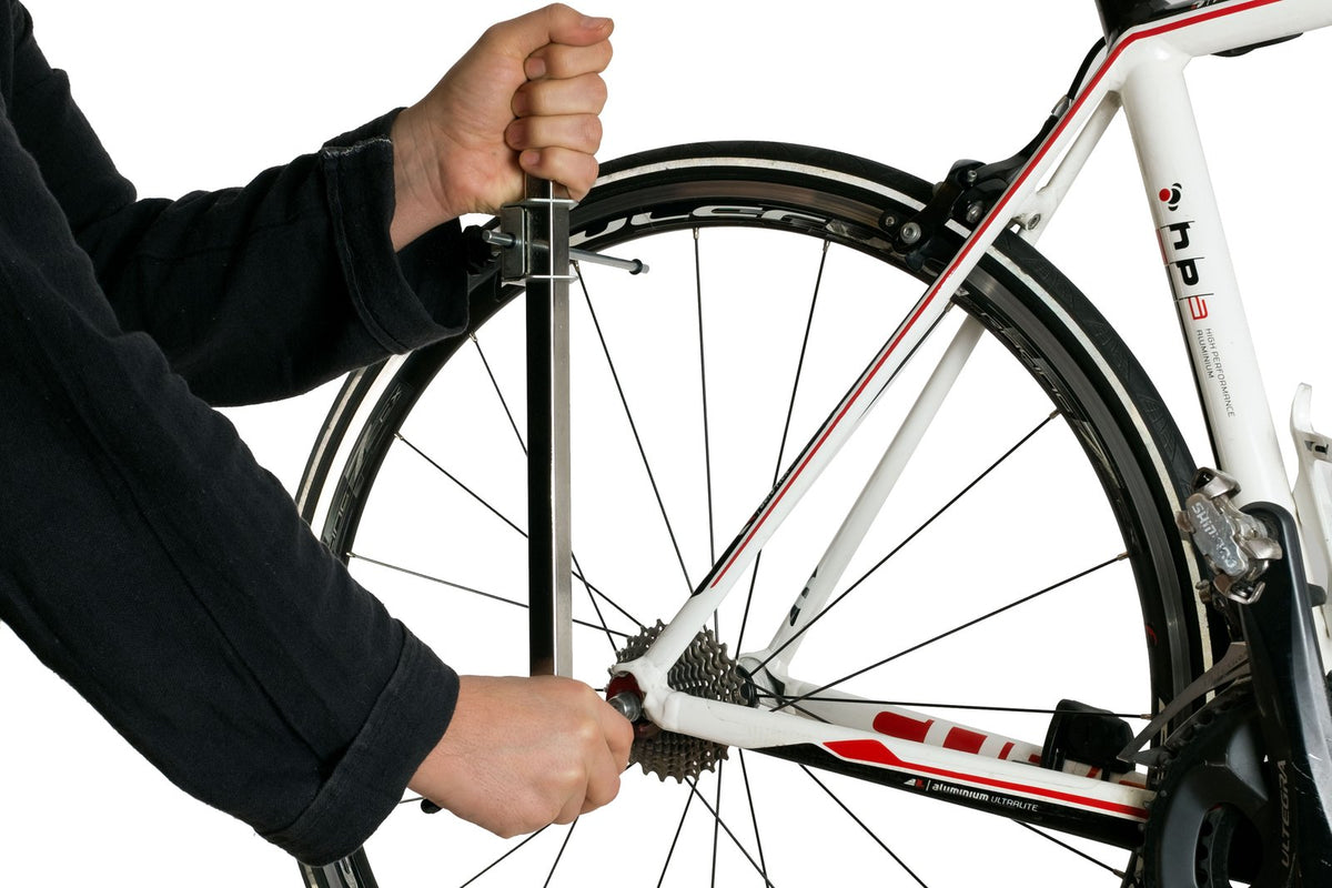 Mechanic checking a road bike's derailleur hanger with the CycloSpirit alignment gauge