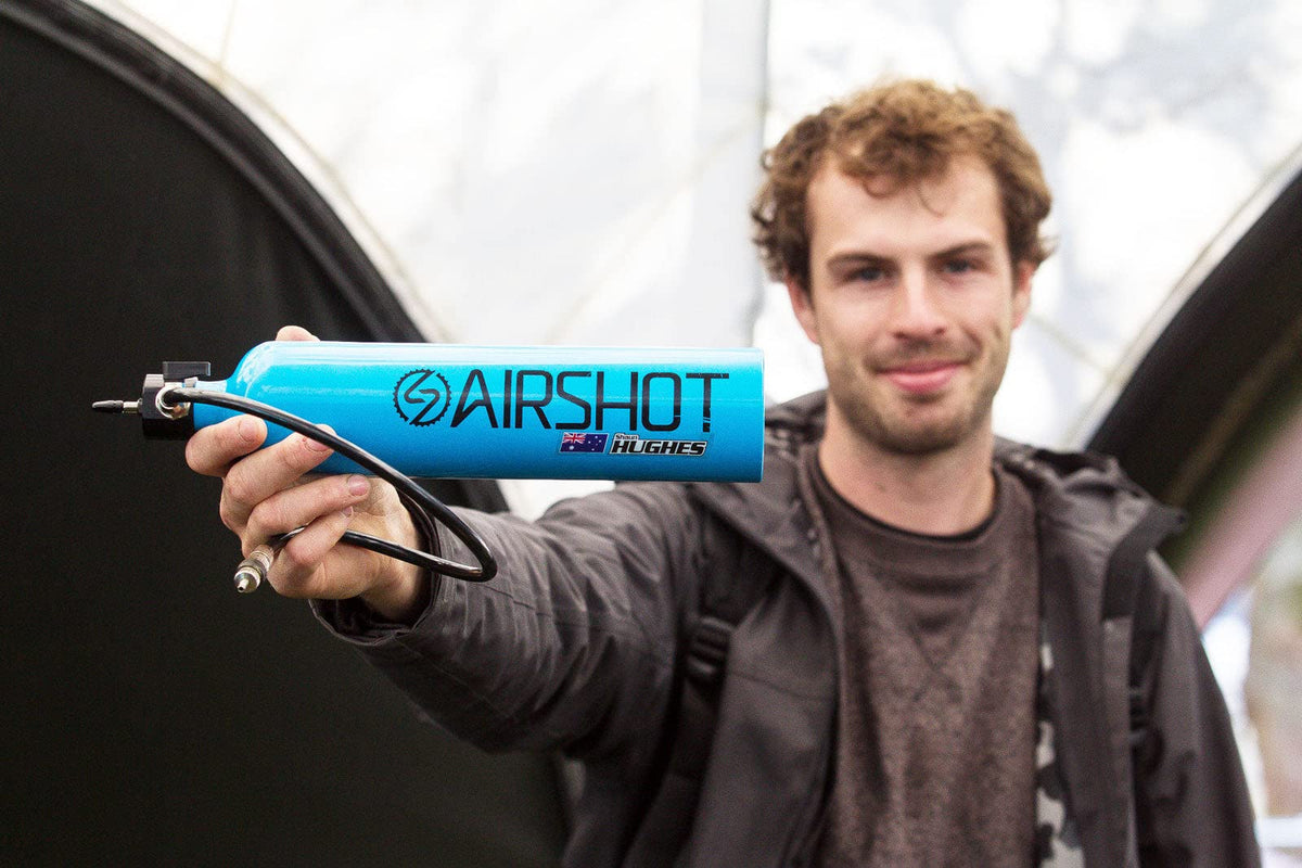 A man holds out a blue Airshot tubeless inflator