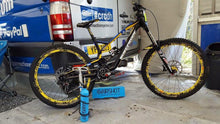 Airshot inflator and its box on the floor beside a downhill mountain bike