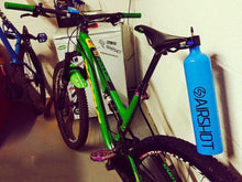 Airshot inflator hanging from the saddle of a green mountain bike in a workshop