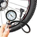 Inflator gauge held in one hand, its head clamped on the valve of a mountain bike tire