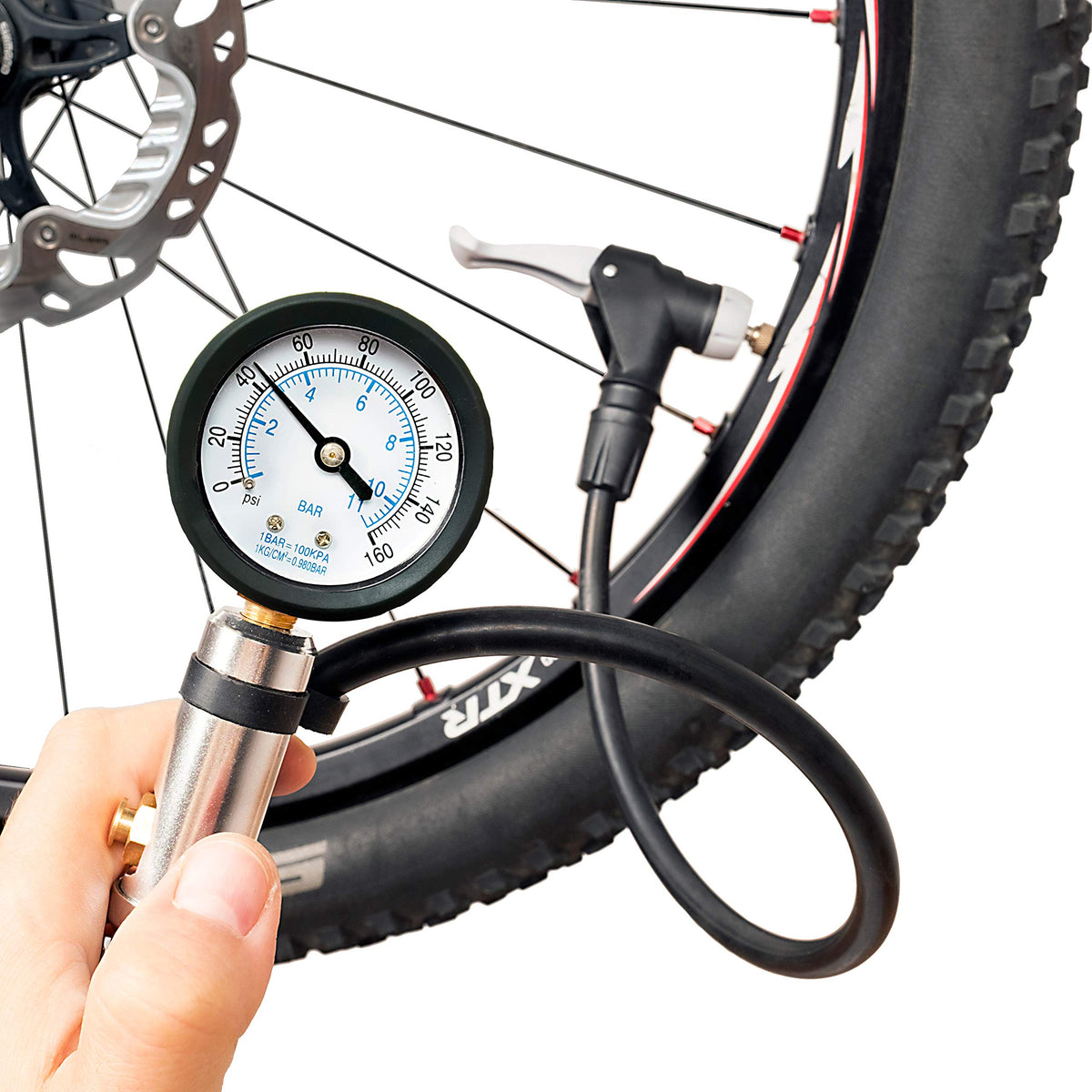 Inflator gauge held in one hand, its head clamped on the valve of a mountain bike tire