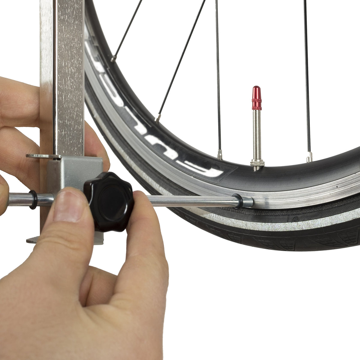 Hand setting the gauge's sliding indicator against the wheel rim