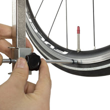 Hand setting the gauge's sliding indicator against the wheel rim