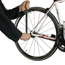 Mechanic holding the alignment gauge against the rear wheel of a road bike